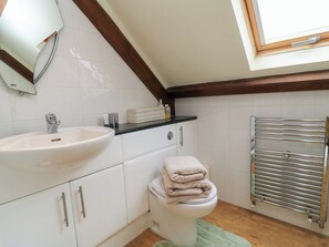 A bathroom with a white sink, a toilet, a towel rack, and a window. - The Coach House (Dorchester)