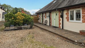 A building with a green door, a wheel in the doorway, and a sign indicating private parking. - The Coach House (Dorchester)