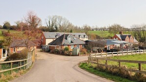 A rural road leading to a row of houses with a green field and trees in the background. - The Coach House (Dorchester)