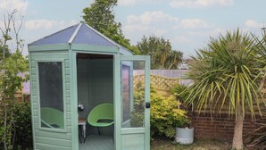 A small, light green wooden shed with a peaked roof, a door, and a window. - The Coach House (Dorchester)