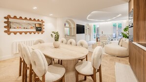 Un salon moderne avec une table de salle à manger ronde, des sièges confortables, un grand miroir et une vue sur l’extérieur.