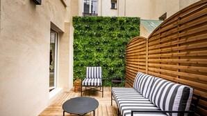 Un espace extérieur accueillant, aménagé avec un banc en bois, un canapé à rayures et une petite table ronde.