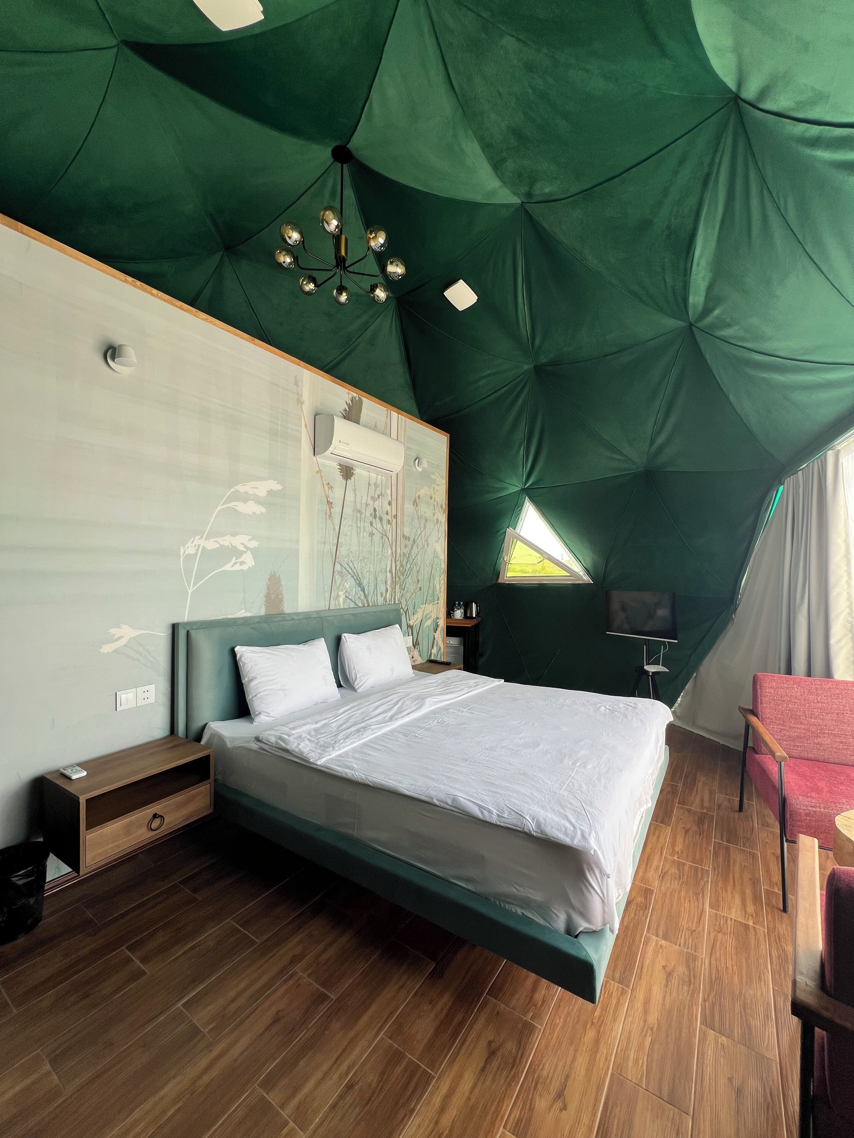 A modern bedroom with a bed, bedside tables, a wall-mounted air conditioner, and a television.