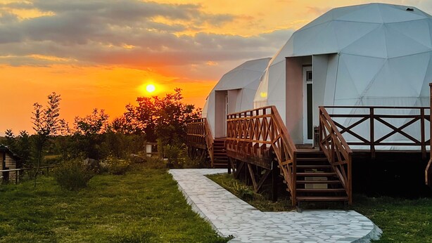 A pathway leading to geodesic dome-style accommodations with wooden railings and a sunset in the background. - Chadir yurd glamp (Ismailli)
