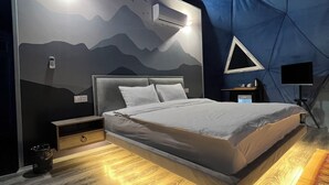 A modern bedroom with a bed, bedside tables, a wall-mounted air conditioner, and a geometric-patterned wall. - Chadir yurd glamp (Ismailli)
