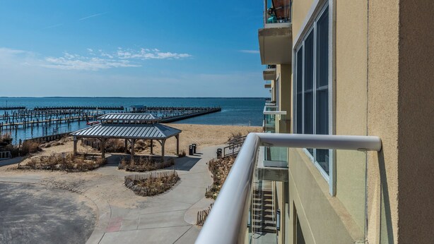 Vista sulla spiaggia con un molo, una zona relax riparata e un edificio con balconi.