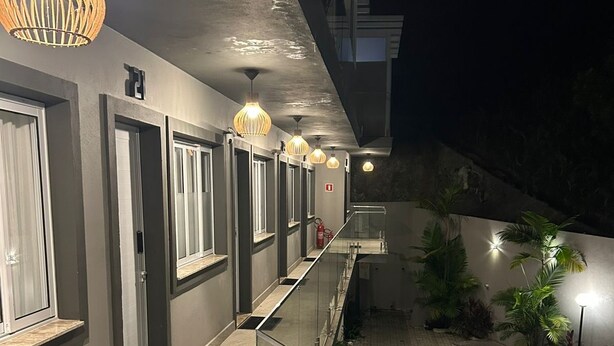 En hotellkorridor med ett glasräcke, en pool och utomhusbelysning.