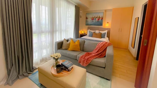Ein Hotelzimmer mit Bett, Sofa, Couchtisch mit Tablett und einem Bild an der Wand.
