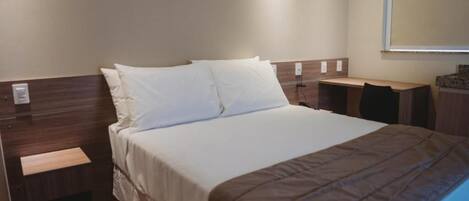 A hotel room with a bed, bedside tables, a desk, and a chair.