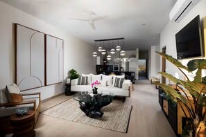 Una sala moderna con una mesa de centro de vidrio, un sofá blanco y un comedor con mesa de madera.