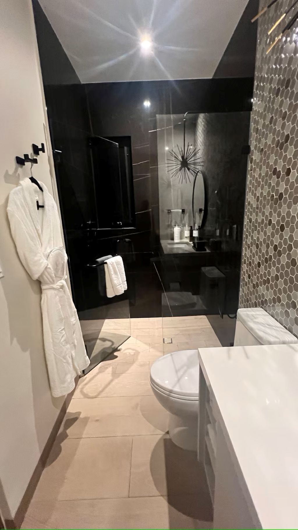 A modern bathroom with a glass shower enclosure, a white bathtub, and a toilet.