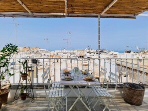 Ein Balkon mit Esstisch, Topfpflanzen und Blick auf die Stadt.