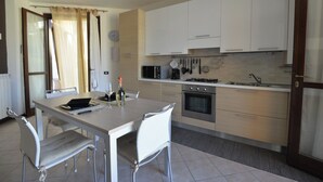 Eine moderne Küche mit Esstisch, Stühlen, Herd, Backofen, Mikrowelle und verschiedenen Küchengeräten.