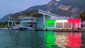 Ein modernes Gebäude mit einem vor Anker liegenden Boot, umgeben von Wasser und Bergen.