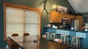 A dining area with a glass table, brown chairs, and a window with blinds. - Moonlight Mountain Lodge at Camelback Mountain! (Tannersville)