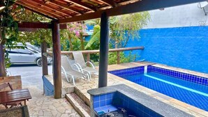 A covered outdoor area with a stone floor, a barbecue grill, and a swimming pool. - VEREDA 7 SUITES (São Sebastião)