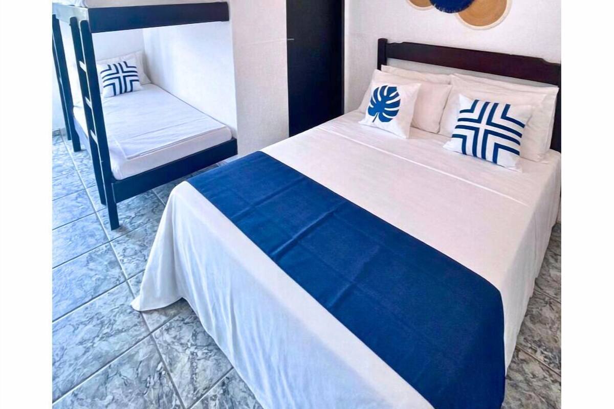 A bedroom with a bunk bed, a single bed, a decorative wall piece, and a door.