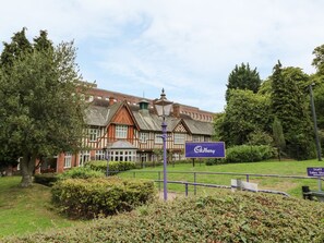 A historic building with a prominent Cadbury sign, surrounded by well-maintained gardens and trees. - Megs Cottage (Stratford-upon-Avon)
