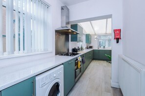 A modern kitchen with a washing machine, a stove, and a fire blanket on the wall. - Chesterton Haven - 3BR Modern & Spacious Living (Chesterton)