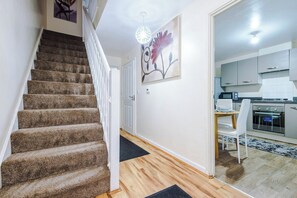 A staircase leading to a room with a kitchen area, a dining table, and a painting on the wall. - Elegant & Spacious Stay - 3BR in Manchester (Greater Manchester)
