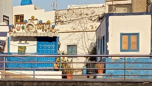 Un bâtiment avec une porte bleue, un balcon et un mur de briques au premier plan.