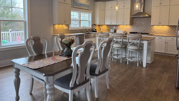 A kitchen with white cabinetry, a dining area with a table and chairs, and a chandelier. - Handicapped- Accessible, Family-Friendly Home near UVA (Charlottesville)