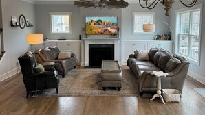 A living room with a fireplace, leather sofas, a coffee table, and a TV. - Handicapped- Accessible, Family-Friendly Home near UVA (Charlottesville)