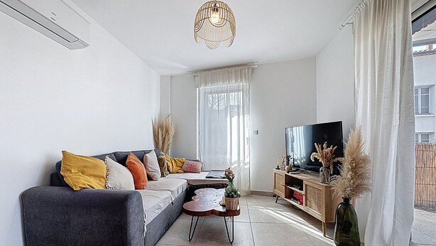 En moderne stue med sofa, fjernsyn og dekorative planter.