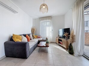 Ein modernes Wohnzimmer mit einer Couch, Fernseher und Zimmerpflanzen.