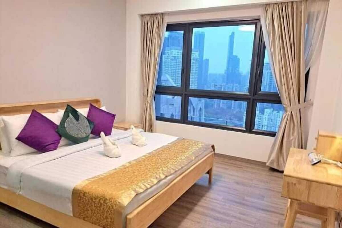 Una habitación de hotel con una cama, una ventana con vistas a la ciudad, un escritorio de madera y una silla.