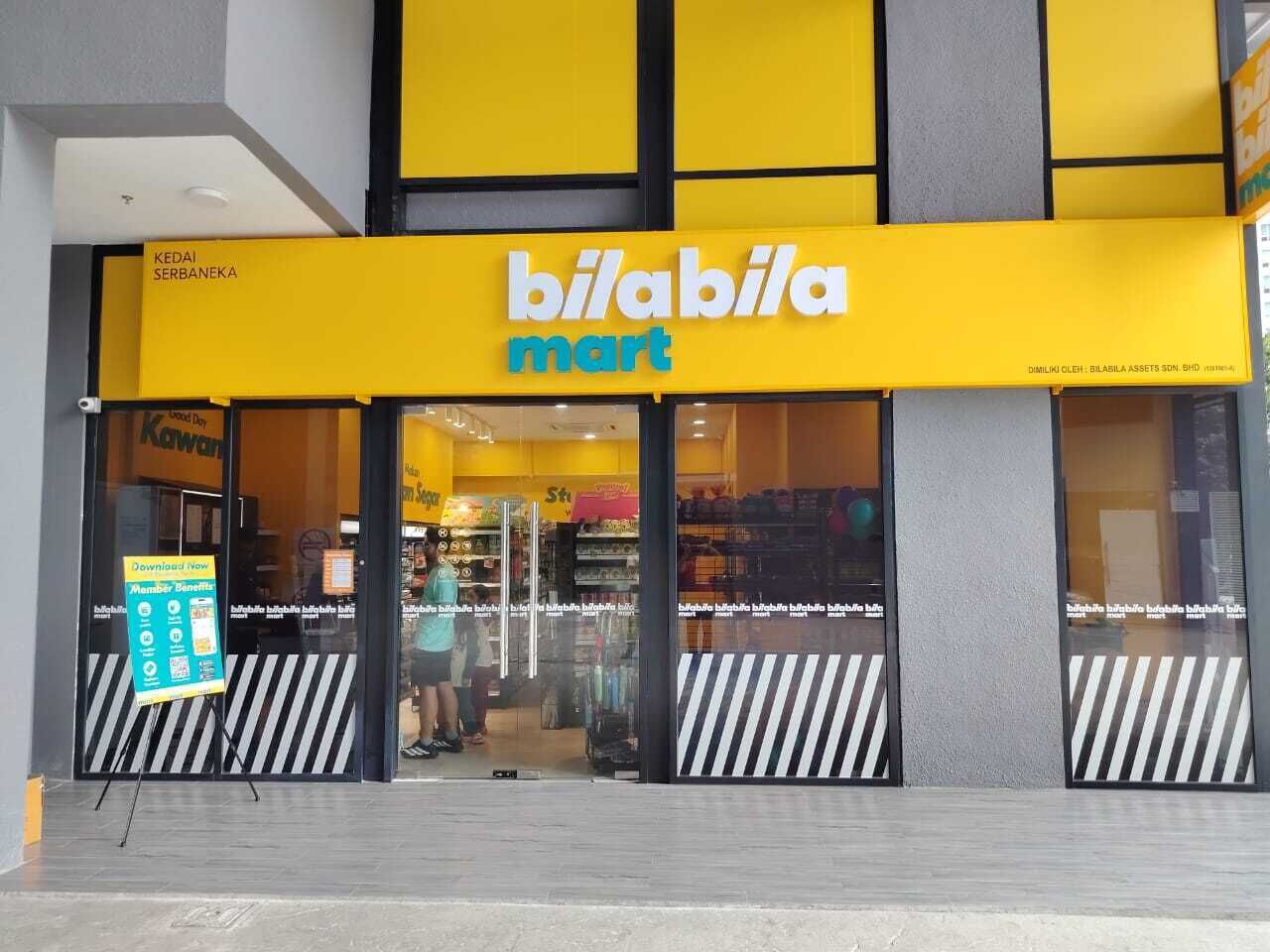 A store with a yellow and black facade, a large glass entrance, and a sign reading 'bilabila mart'.