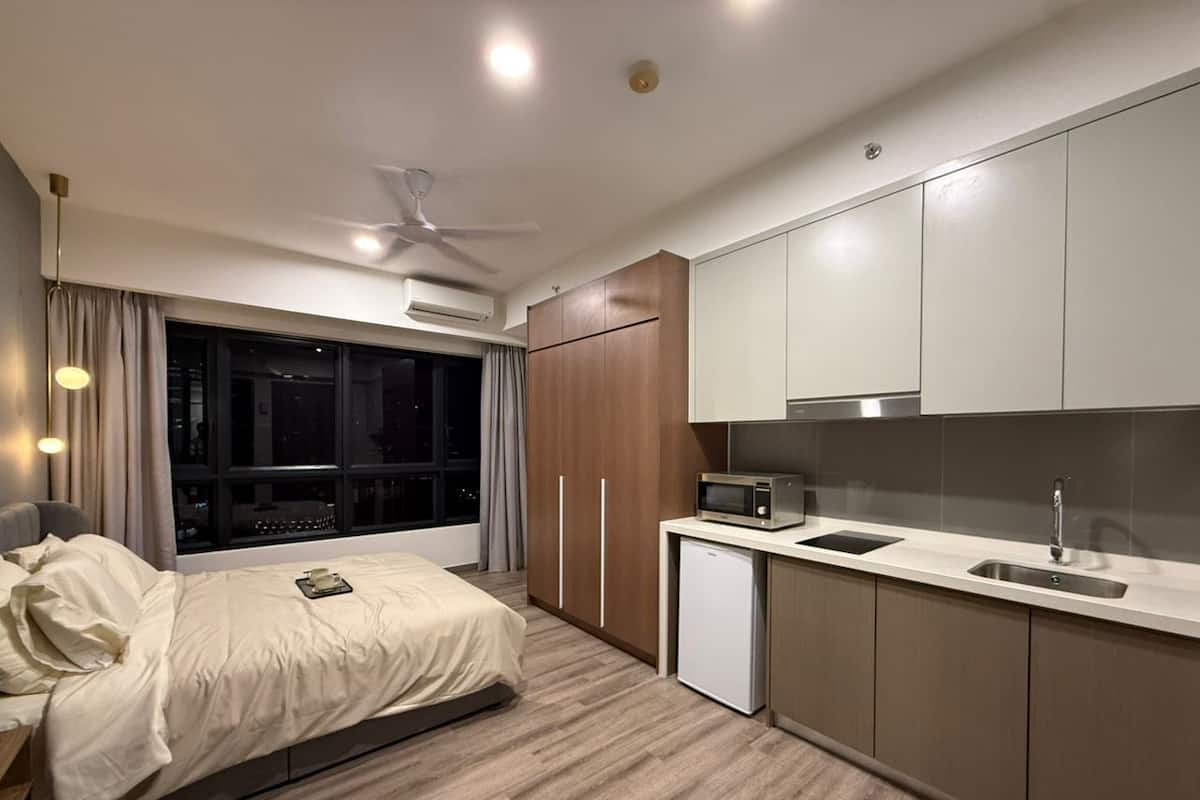Un dormitorio moderno con cama, mesita de noche y ventana con cortinas.