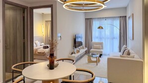 A modern living room with a round dining table, a sofa, a TV, and a large window with curtains. - Agile Grand Prime  suite TRX by KL (Kuala Lumpur)
