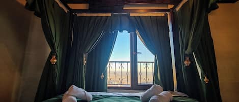Una habitación con cama, cortinas verdes y ventana con vistas.