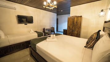 A hotel room with a bed, a TV, a wooden headboard, a small table, and a chair.