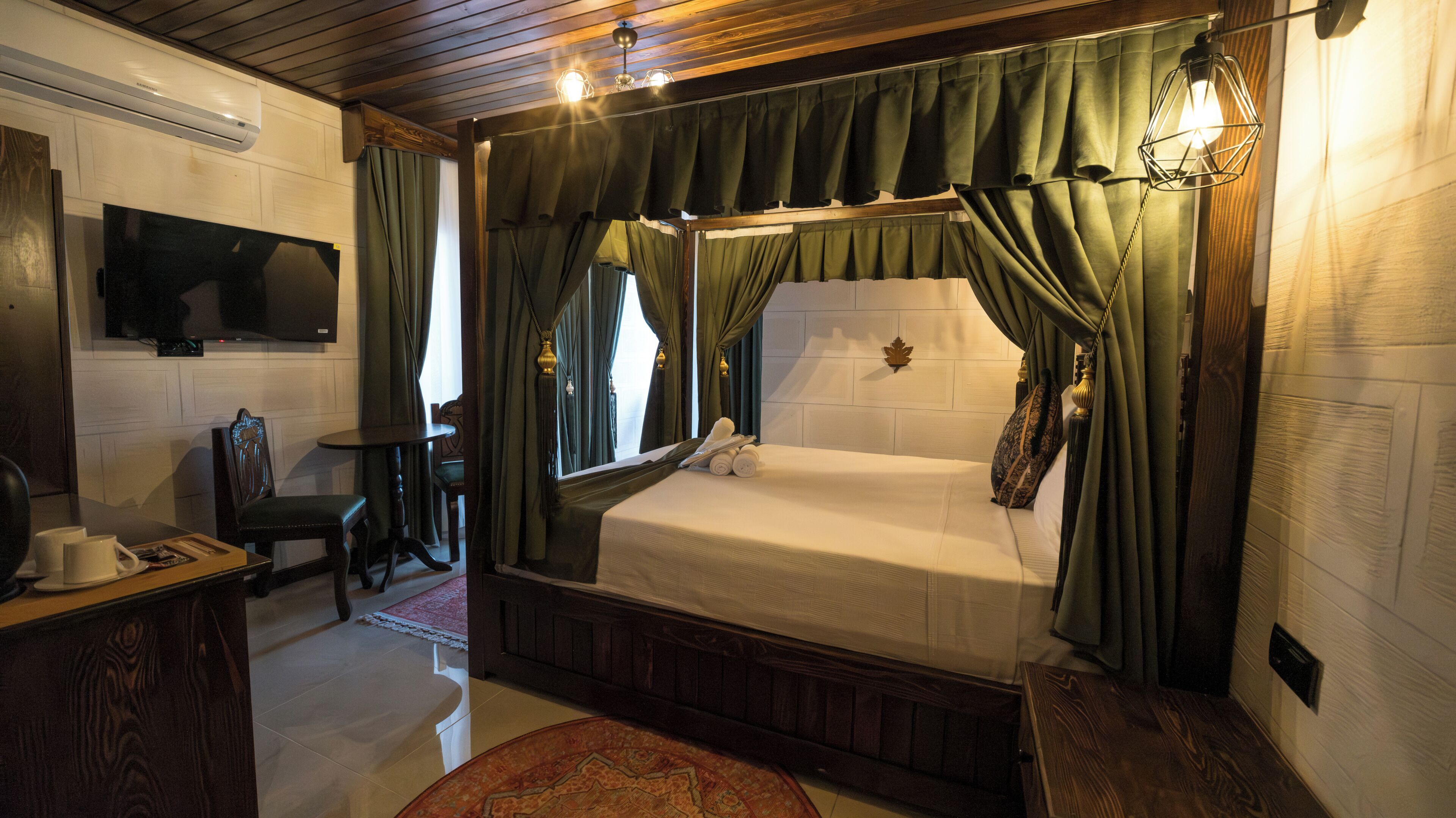 A bedroom with a bed, a TV, a desk, and a chair.