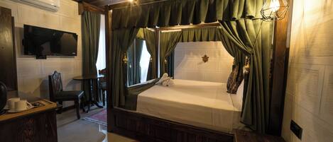 A bedroom with a bed, a TV, a desk, and a chair.