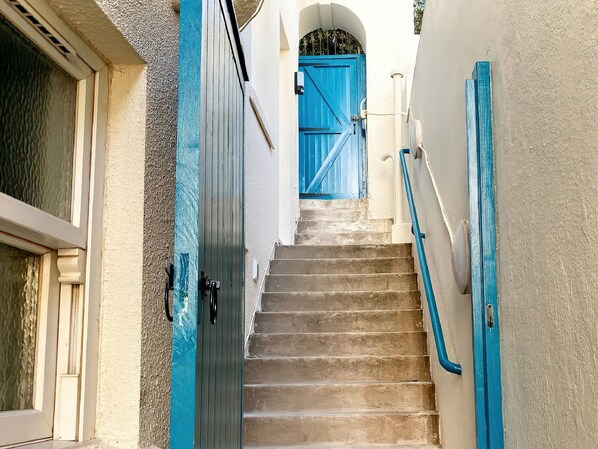 Eine Treppe mit blauen Geländern, die zu einer blauen Tür am oberen Ende führt.