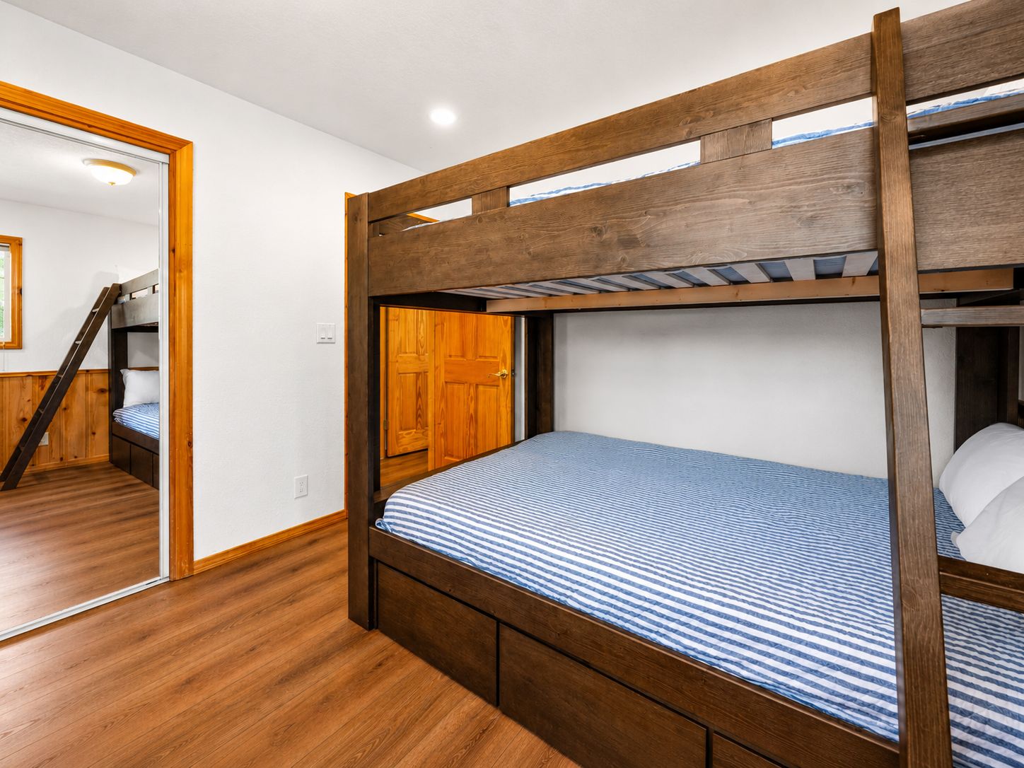 Ein Schlafraum mit Etagenbett, Holzkopfstück, Tür und Treppe.