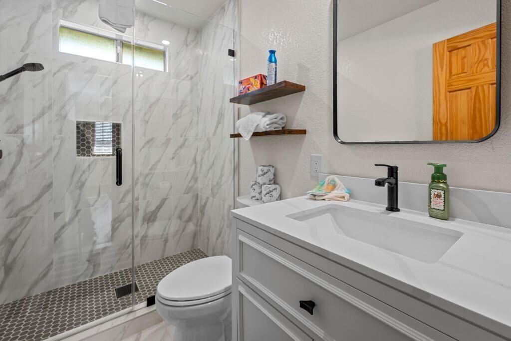 Un baño con ducha de vidrio, lavamanos blanco y espejo.