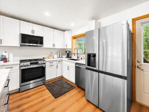 Eine moderne Küche mit weißen Schränken, Edelstahlgeräten, einem eingebauten Backofen und einem Kühlschrank.