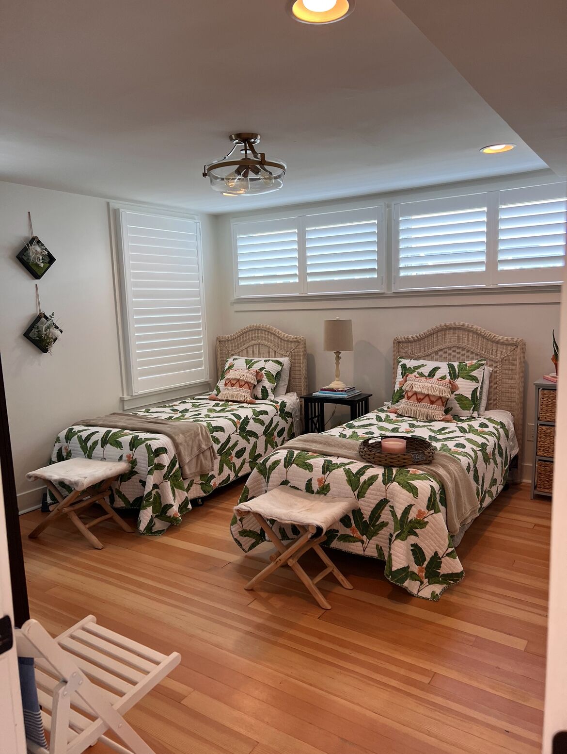 A bedroom with two beds, a ceiling fan, and a window with blinds.