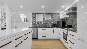 A modern kitchen with white cabinetry, a stainless steel dishwasher, a microwave, and a built-in oven.