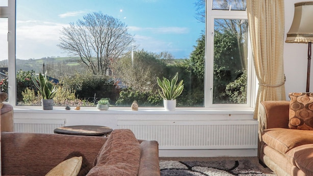 A living room with a large window, a sofa, a lamp, and a radiator. - 7 Erme Drive (Ivybridge)