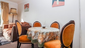 A dining area with a round table, floral tablecloth, and four chairs. - 7 Erme Drive (Ivybridge)