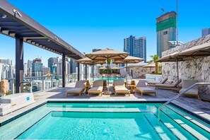 A rooftop pool with lounge chairs and umbrellas, surrounded by a city skyline. - Domus Brickell Deluxe Studio Suite (Miami)