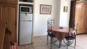 Eine kleine Küche mit Kühlschrank, Mikrowelle und Holzschränken.