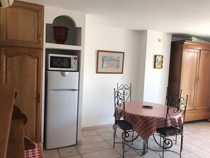 Eine kleine Küche mit Kühlschrank, Mikrowelle und Holzschränken.