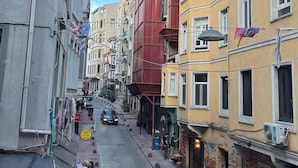 Una calle urbana estrecha flanqueada por edificios de varios pisos, algunos con balcones y tiendas en la planta baja.