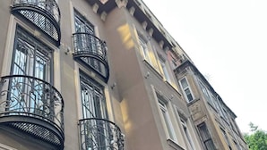 Un edificio de varios pisos con balcones de hierro forjado negro ornamentados, ventanas amplias y un letrero que indica una institución religiosa.
